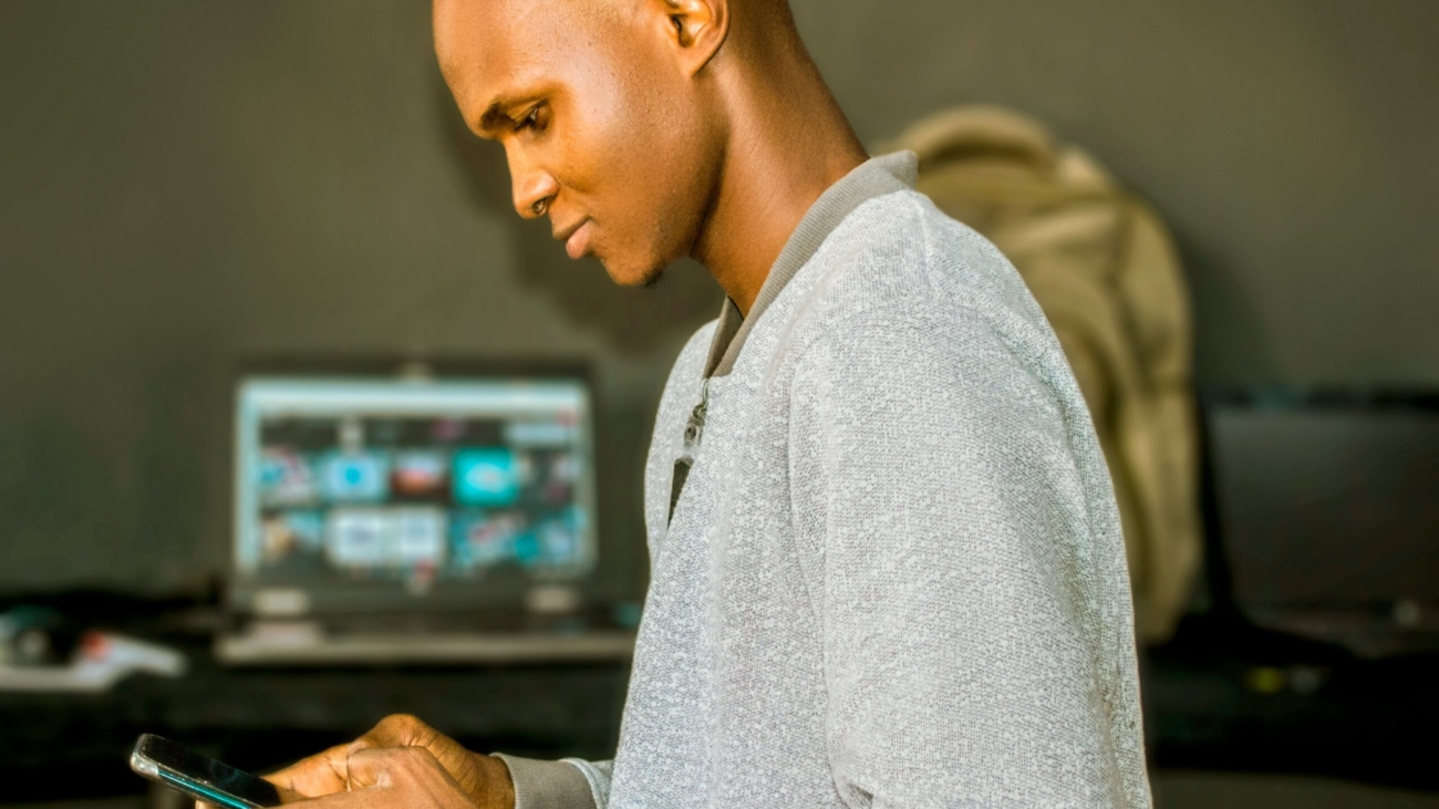 Young man on phone and conputer in background